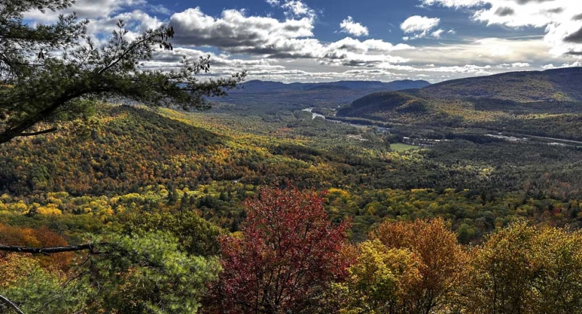 A vast mountainous landscape is dotted in the colors of fall 